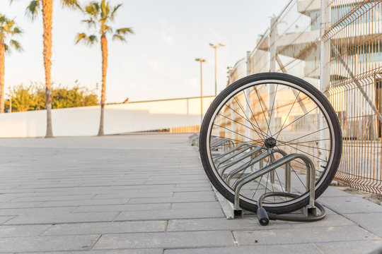 Fototapeta Stolen bicycle, Chained front bicycle wheel locked. A damaged bike wheel is all that is left, a single bicycle wheel on the street due to stealing.