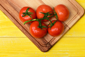 Tomatoes, cherry on vine on cutting board, yellow vintage background