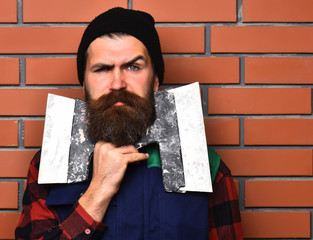 bearded worker man holding spatulas with serious face