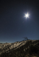 the moon and stars over a mountain range 