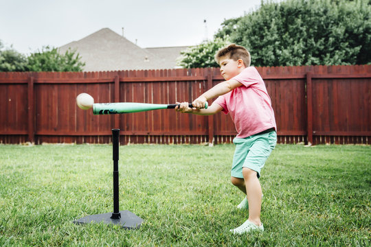 Boy playing with t-ball in backyard