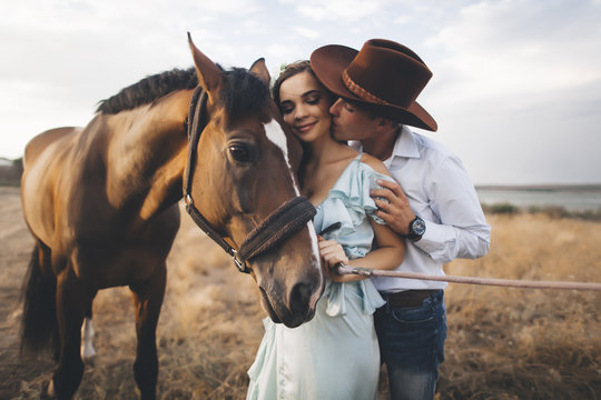 Caucasian cowboy kissing woman on cheek near horse