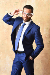 Obraz premium Businessman in stylish blue suit posing with retro white glasses