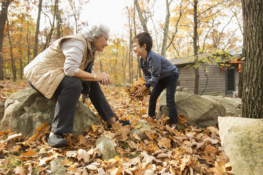 Grandmother and grandson playing with autumn leaves