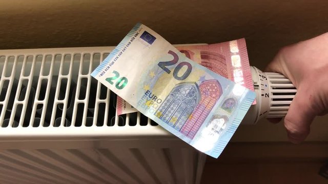 Fallende Heizkosten symbolisiert durch Geldscheine auf Heizung