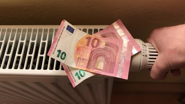 Steigende Heizkosten symbolisiert durch Geldscheine auf Heizung