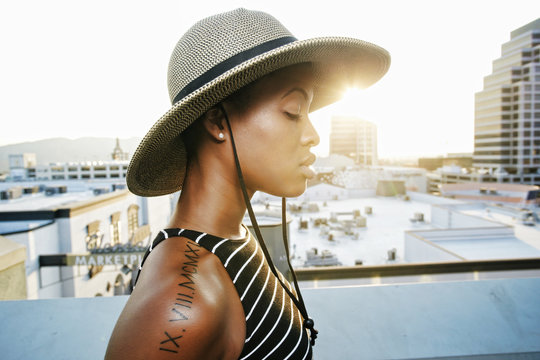 Pensive Black woman wearing sun hat on rooftop
