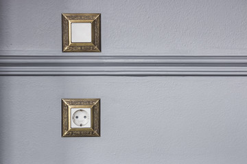 A socket and a switch on the wall decorated with a baguette.