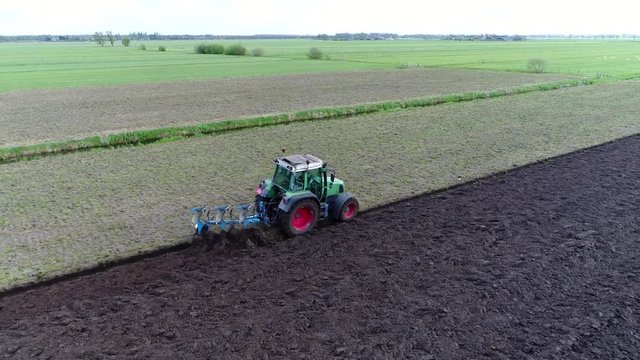 Aerial near modern tractor ploughing also known as plowing land a plough or plow is tool farm implement used in farming for cultivation of soil in preparation for sowing seed planting to loosen soil