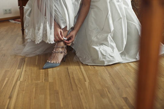 Bride puts on blue wedding shoe