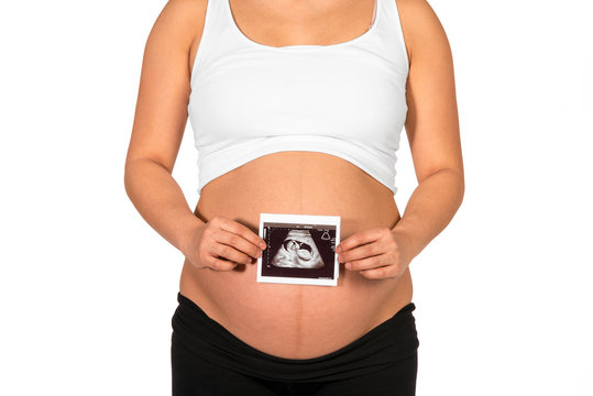 Pregnant woman holding ultrasonogram in front of her bare belly