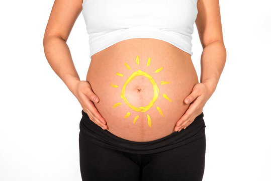 Yellow sun painted on bare belly of pregnant woman