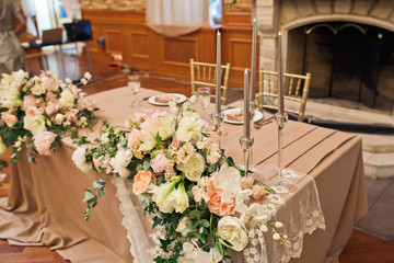 Tall silver candles stand on dinner table prepared for newlyweds