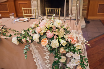 Tall silver candles stand on dinner table prepared for newlyweds