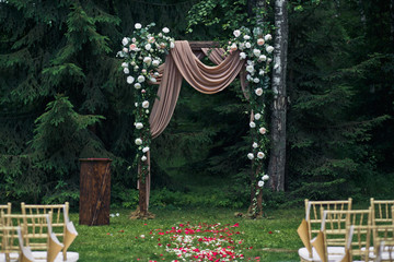 Wedding altar made of wood stands before dark green forest