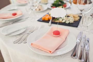 Stick with white card put in a red macaroon stands on dinner plate