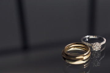 Wedding rings made of yellow and white gold lie on the glass table