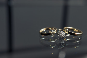 Wedding rings made of yellow and white gold lie on the glass table