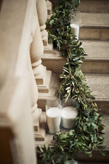 Green garland lies on the stairs with candles