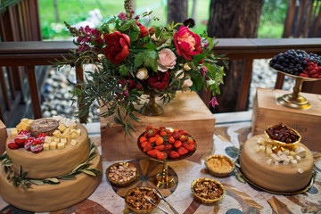 Snacks and fruits stand served before bouquet of peonies