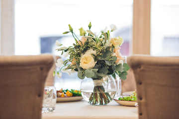 Gorgeous bouquet of white flowers and greenery stands on rich served table