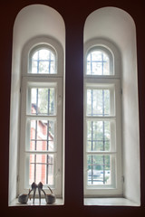 White shoes with open toe stand on windowsill of tall window