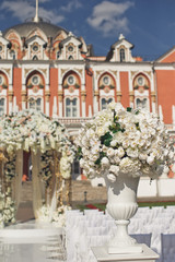 Fototapeta na wymiar Greek vase with white flowers stands on the pillar before wedding altar
