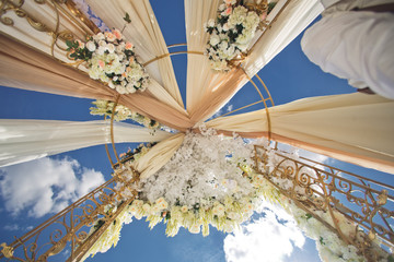 Look from below at wedding altar decorated with brown cloth and white flowers