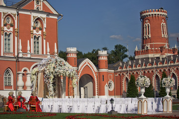 Obraz premium Beautiful wedding altar made of brown and white cloth and rich garlands of flowers stands before red house
