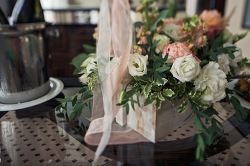 White wooden box with roses stands on glass table