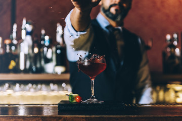 Barman is making cocktail at night club.