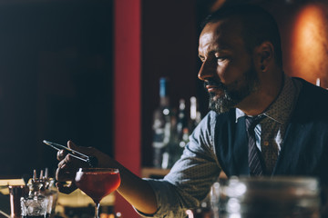 Barman is making cocktail at night club.