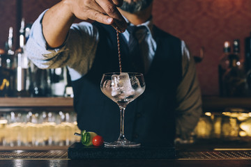 Barman is making cocktail at night club.