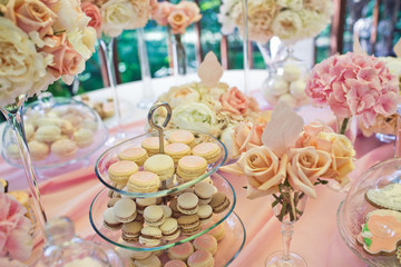 Tired dish with macaroons stands on the table with sweets