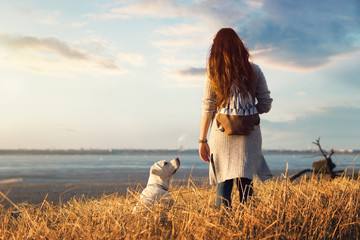 Junge Frau mit Labrador Retriever Hund Welpe im Urlaub am Strand bei Sonnenuntergang