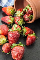 Red ripe strawberries spilled on table from a bowl.