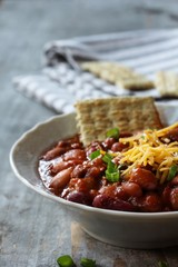 Bean Chili Bowl topped with cheese and green onions, selective focus