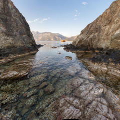 Cove in the clear sea on the background of the rocky mountains