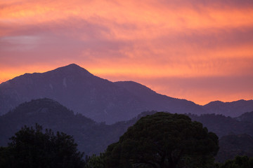 Obraz premium Red sunset in the mountains landscape with sunny beams.