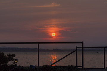 Fototapeta na wymiar Setting sun with glass rail over the sea