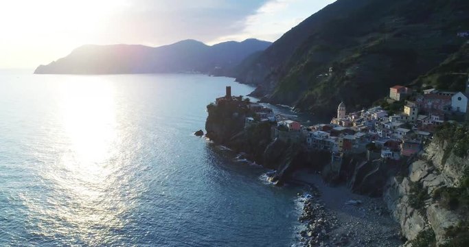 aerial view of travel landmark destination Vernazza, a small mediterranean sea town, Cinque terre National Park, Liguria, Italy. Sunset with cloud and flare. 4k aerial drone backward video shot