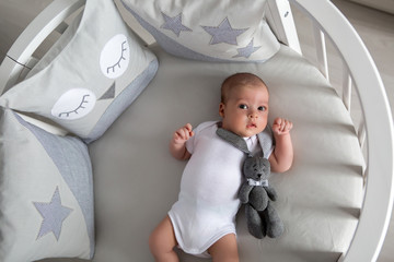 Newborn boy lies in a round bed on his back