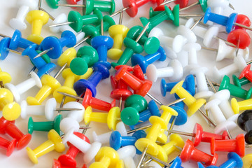 Many colorful push pins on the background, close-up