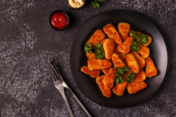 Chicken naggets with sauces on dark background.