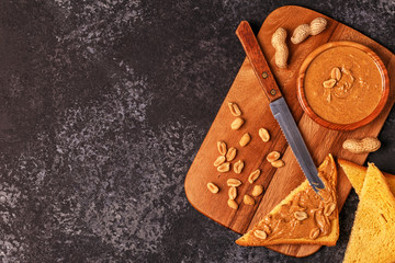 Bowl of peanut butter on wooden board.