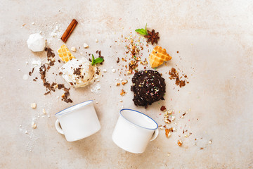 Scoops of ice cream in a variety of delicious and ingredients with two enamel mugs, flat lay