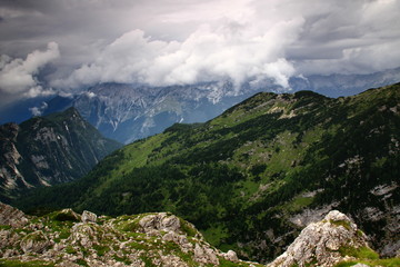 The misty Trenta Valley covered with storm clouds with the green slopes of Zadnjiski Ozebnik peak from Triglav Lakes Valley, Julian Alps, Triglav National Park, Slovenia
