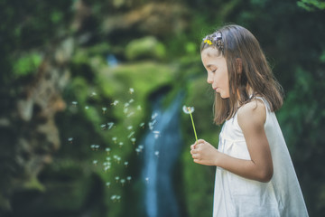 Little girl plays with flowers by a river