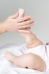 Fototapeta na wymiar baby getting feet massage in a white room