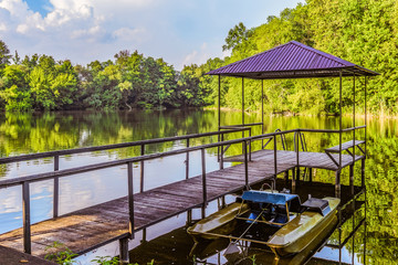 Footbridge with a gazebo and small pier for pleasure pedal catamaran on the lake shore. Dock for pedal boat and a quiet holiday in nature.